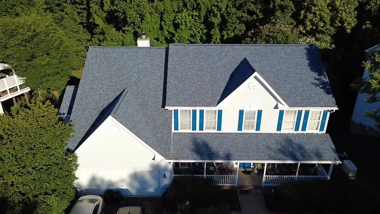 Aerial view of a completed gray shingle roof with blue shutters