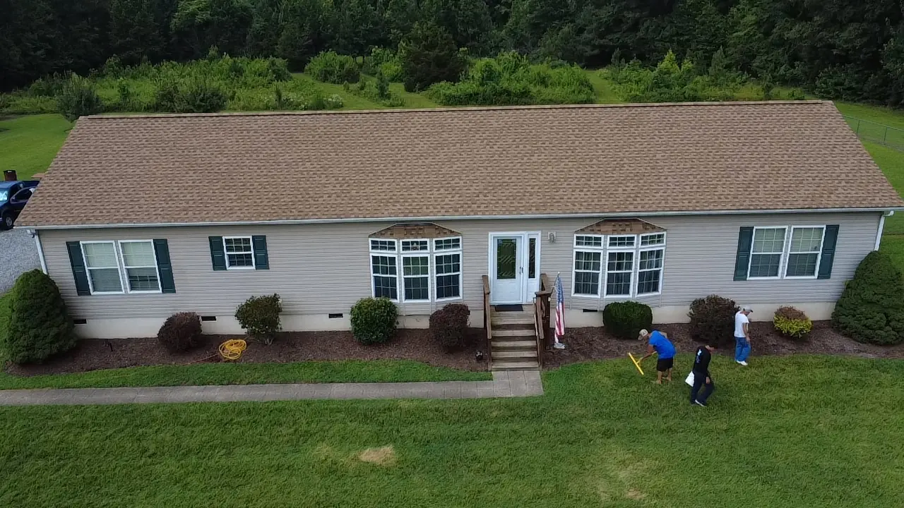 Crew finishing up around a home with a new brown shingle roof
