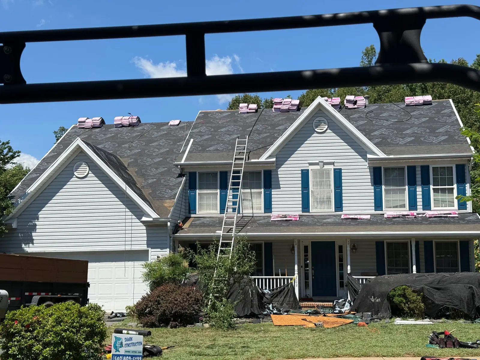 Roofing crew working with ladders on a shingle roof repair in the Fredericksburg area